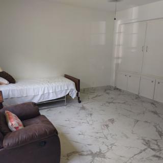 A minimalist bedroom with a single bed and white tiled floor.