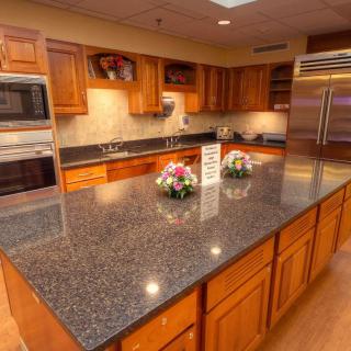 A spacious kitchen featuring granite countertops, wooden cabinets, and stainless steel appliances.