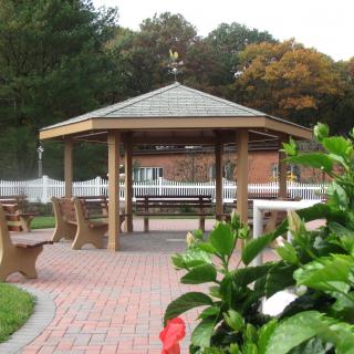 A well-maintained gazebo surrounded by benches and a paved walkway in a park setting.