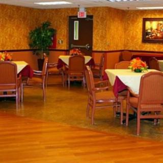 A well-decorated dining room with several tables and chairs, featuring a wooden floor and indoor plants.