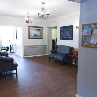 A cozy living room interior with wood flooring, sofas, a chandelier, and artwork on the walls.