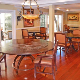 A cozy dining area with wooden floors, round tables, and a classic chandelier.