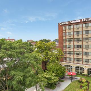 Exterior view of a hotel building surrounded by trees on a clear day.