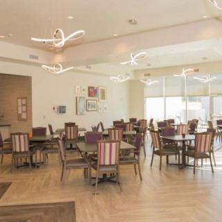 A spacious and elegantly designed dining area with modern lighting and neatly arranged tables and chairs.