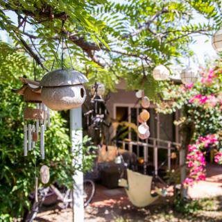 A charming garden with lush greenery, colorful flowers, and decorative wind chimes under a sunny sky.