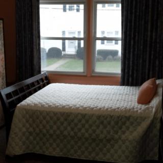 A bedroom with a bed positioned near a window, allowing natural daylight to enter the room.