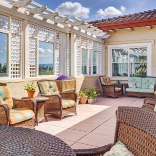 A sunny patio with wicker furniture and decorative plants offers a relaxing outdoor space.