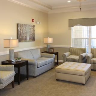 A cozy and well-lit living room with sofas, chairs, and a large window.