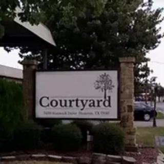 An outdoor sign for Courtyard hotel on a landscaped area.