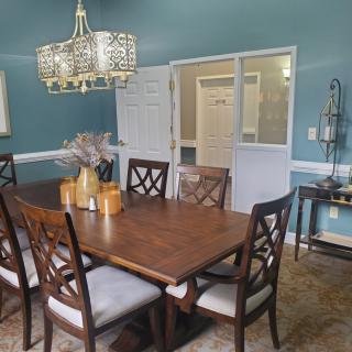 A stylish dining room featuring a wooden table with matching chairs and an elegant chandelier.