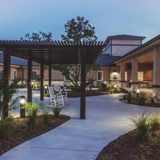 A serene residential outdoor space featuring a pergola, garden path, and evening lighting.