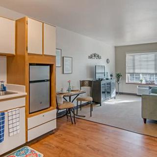 A cozy open-plan apartment featuring a compact kitchen and a living area with a dining table.