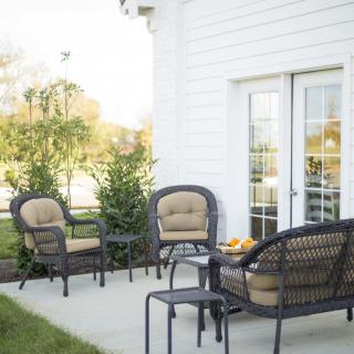 A cozy outdoor patio seating area with chairs and a table set against a white house.