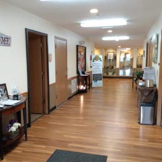 A well-lit hallway with wood flooring, featuring office decor and furniture.
