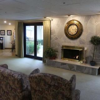 A cozy living room with a fireplace, large wall clock, and plush seating.