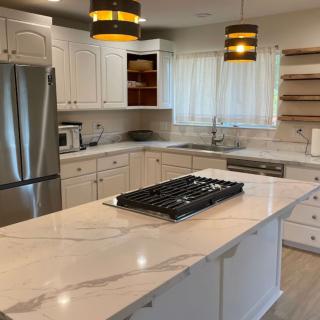 A modern kitchen with a marble countertop island and stainless steel appliances.
