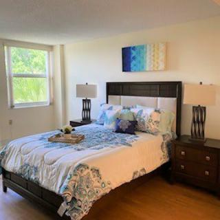 A well-decorated bedroom with a large bed, nightstands, and stylish artwork on the wall.