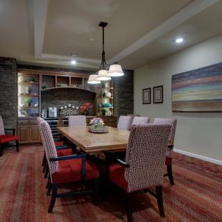 A modern dining room with a wooden table, upholstered chairs, and elegant lighting.