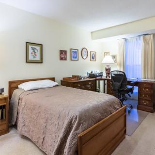 A cozy bedroom with a single bed, desk, and decor on the walls.