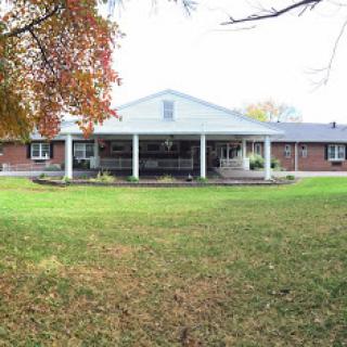 A spacious residential home with a welcoming porch surrounded by a lush green lawn.