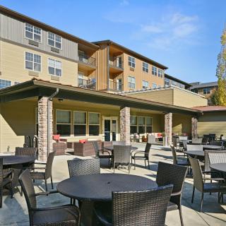 Outdoor patio area with tables and chairs in front of a residential building.