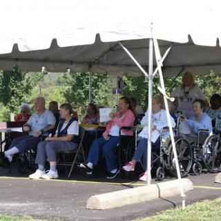 A group of elderly individuals enjoying a community event under a tent.