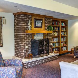A cozy living room with a brick fireplace, bookshelves, and comfortable seating.