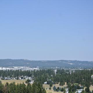 A scenic view of a countryside with trees and hills under a clear blue sky.