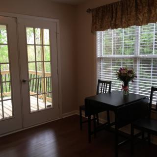 A cozy dining area with a small table, chairs, and flowers by a window letting in natural light.