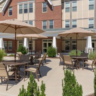 An outdoor patio area with tables, chairs, and umbrellas in front of a building.