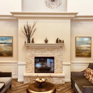 A modern living room with a central fireplace, elegant artwork, and stylish furnishings.