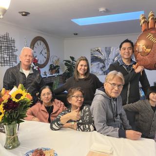 A family gathered around a dining table for a group photo indoors.