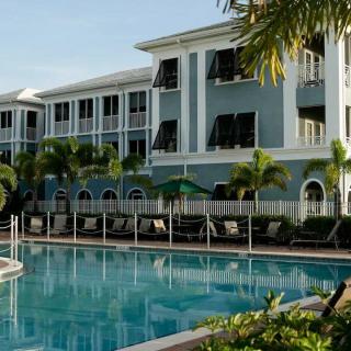 A luxurious resort featuring a large swimming pool surrounded by palm trees and elegant architecture.