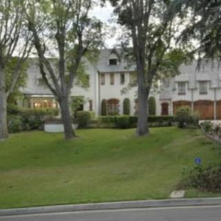 A suburban house with a large front lawn and surrounding trees.
