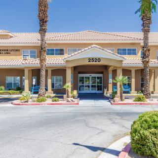 A sunny day view of a two-story building with palm trees framing the entrance.