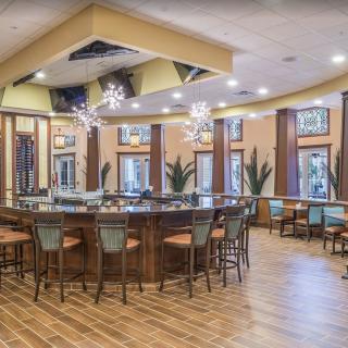 A stylishly designed bar with ample seating, featuring modern chandeliers and a polished wooden floor.