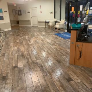 A spacious waiting area featuring wood-look flooring and comfortable seating.