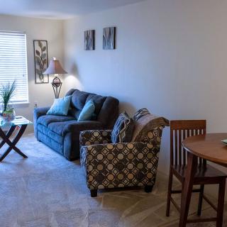 Cozy living room with a sofa, armchair, and dining area.