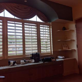 A cozy room featuring a window with blinds and open shelving.