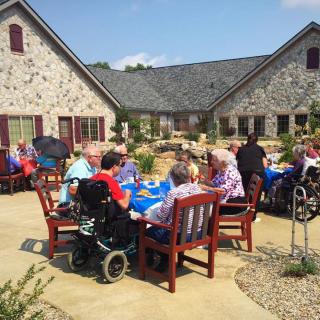 A group of seniors enjoying an outdoor gathering in a courtyard with stone buildings.