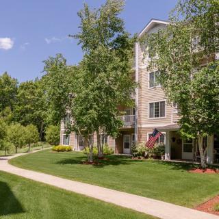 An apartment building surrounded by lush greenery and well-maintained landscaping on a sunny day.