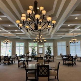 A spacious dining area with elegant chandeliers and neatly arranged tables and chairs.