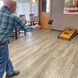 An elderly man enjoying a game of cornhole indoors.