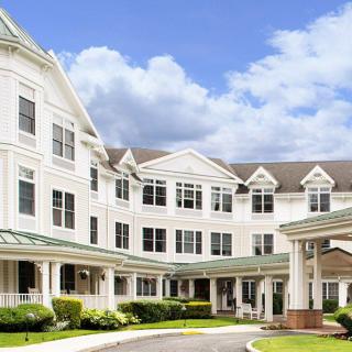 A large, elegant residential building under a bright blue sky with clouds.