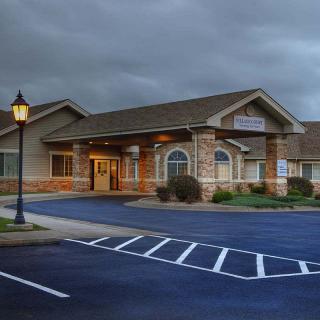A building with a parking lot under a cloudy sky.