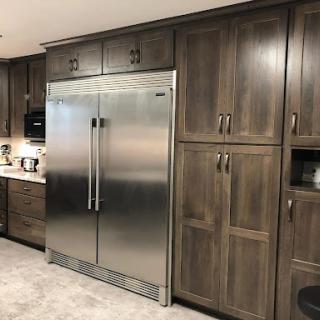 A contemporary kitchen featuring a stainless steel refrigerator and dark wooden cabinetry.