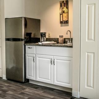Compact kitchen area with a mini fridge, white cabinets, and countertop appliances.