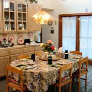 A cozy dining room with a floral tablecloth, elegant chandelier, and neatly set table.