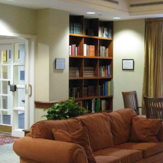 A cozy living room with a brown sofa and a bookshelf filled with books, creating a comfortable reading area.