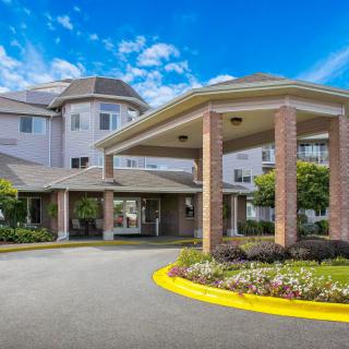 A residential building with a welcoming entrance and landscaped surroundings under a partly cloudy sky.